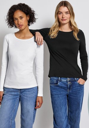 Deux t-shirts à manches longues : un en blanc, un en noir. Les deux sont en tissu doux avec un col rond, associés à un jean bleu.
