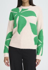 Strickpullover in sanftem Beige mit markanten grünen Blattmustern. Verfügt über lange Ärmel und einen Rundhalsausschnitt, mit lockerem Schnitt und strukturierter Stoffqualität.