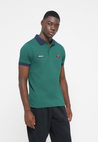 Zelená polokošela s námorníckym golierom, krátkymi rukávmi a nášivkou loga na hrudi. Vyrobená z bavlny s hladkou textúrou. Jednoduchý dizajn.
