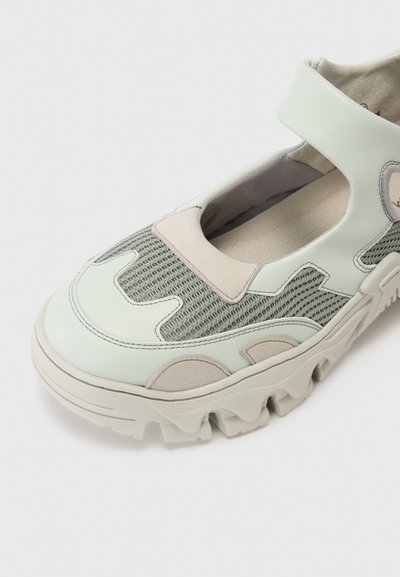 Chaussure de style Mary Jane verte et grise avec une tige en maille texturée, des accents en cuir lisse et une semelle en caoutchouc épaisse avec des bords dentelés.