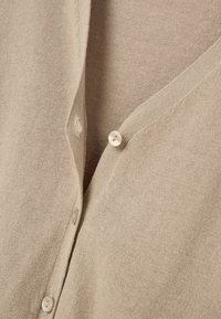 Beige svetřík vyrobený z měkkého materiálu, s výstřihem do V, čtyřmi kulatými knoflíky a hladkým, texturovaným povrchem.