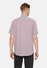Camisa de manga corta en un patrón de cuadros en rojo claro y blanco, hecha de una tela texturizada, con un collar estándar y un ajuste relajado.