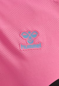 Różowy materiał o teksturowanym splocie z niebieskim i różowym logo Hummel w kształcie stylizowanej pszczółki.