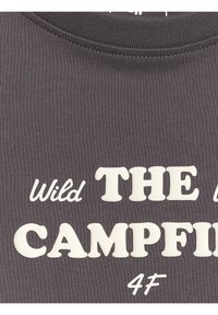 Tissu gris foncé avec texte blanc mentionnant "Wild THE CAMPFIRE 4F" en polices mixant script et bloc.