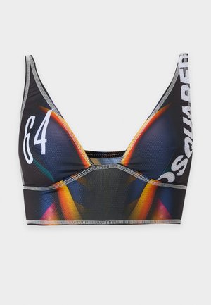 Femme debout pieds nus portant un bikini à motifs noirs, orange et gris avec le numéro 64 sur le haut sur fond blanc.