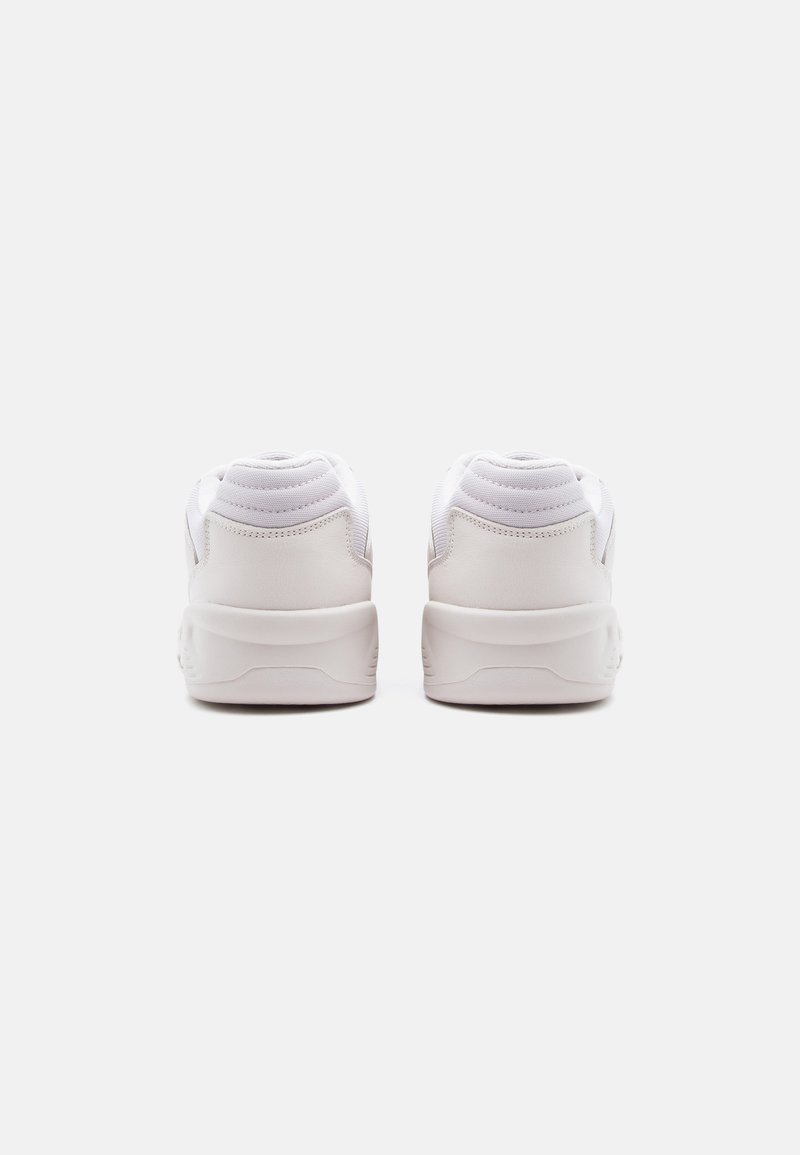 Pair of white sneakers viewed from the back, featuring padded collars and thick soles on a plain light background.