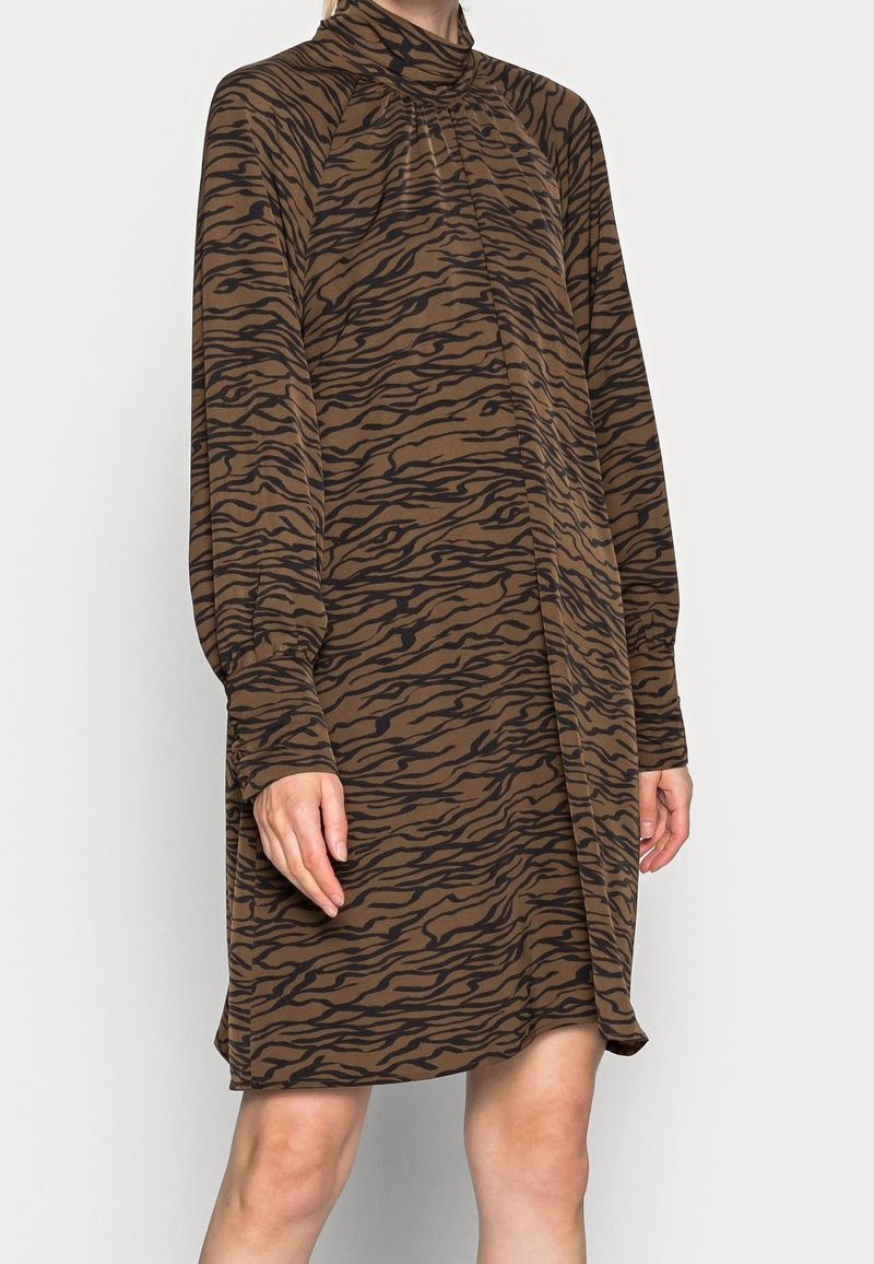 Brun klänning med ett mönster av svarta tigerränder, långa ärmar, hög krage och en lös passform som faller över knäna.