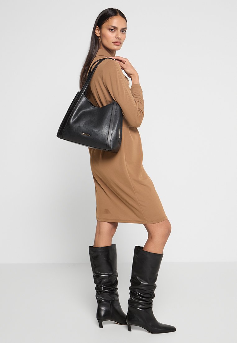 Zwarte leren schoudertas met een gestructureerde vorm en een gladde textuur, voorzien van dubbele schouderbanden en een subtiele logodetail aan de voorkant.