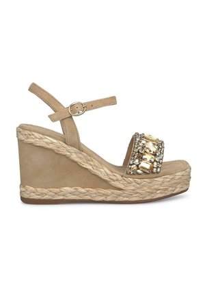 Beige wedge sandal with a textured jute sole, adorned with a jeweled strap and a buckle detail. Smooth material and open toe design.