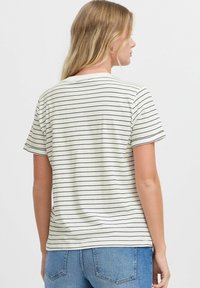 T-shirt rayé beige clair avec de fines lignes horizontales noires. Manches courtes, col rond, coupe décontractée, fabriqué en coton doux.