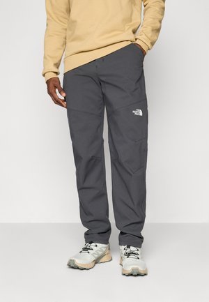 Gray, lightweight outdoor pants with knee accents and The North Face logo. Worn with a beige sweater and light running shoes.