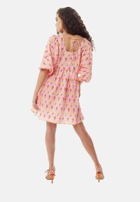 Pink floral dress with short, puffed sleeves and a back tie detail. Features a gathered waist and a soft, textured fabric.