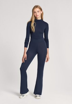 Body blu navy a maniche lunghe con scollatura alta, abbinato a pantaloni a zampa d'elefante coordinati. Tessuto liscio e design aderente.