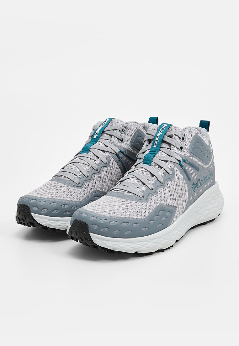 Ein Paar graue und tealfarbene Columbia Sportschuhe mit Netzobermaterial, gemusterten Sohlen und Zuglaschen auf einem schlichten weißen Hintergrund.