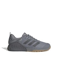 Baskets de sport grises avec tige en mesh, semelle en caoutchouc et accents texturés. Comprend trois rayures noires et un système de laçage ajustable.
