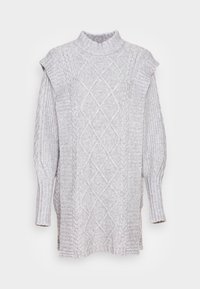 Ljusgrå stickad tröja med hög krage, texturerade kabelmönster, ribbade ärmar och sidoklipp. Har en dekorativ knappaccent.