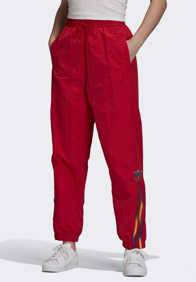 Červené nylonové sportovní kalhoty s elastickým pasem, postranními kapsami a barevným pruhovaným akcentem po stranách, s logem blízko kotníku.
