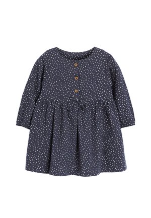 Robe marine à manches longues, col rond et jupe froncée. Présente des motifs triangulaires blancs, des boutons en bois et une ceinture à la taille.