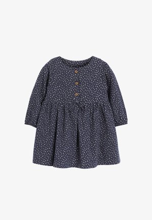 Mørkeblå kjole med lange ærmer, rund halsudskæring og en flæse nederdel. Har hvide trekantede mønstre, træknapper og et bælte i taljen.