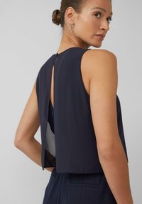 Marineblauwe mouwloze top met een cropped ontwerp, voorzien van een opening met sleutelgat aan de achterkant en een doorschijnende paneel voor extra detail en textuur.