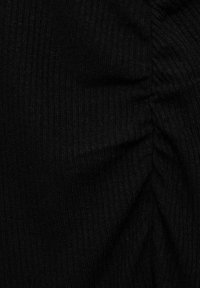 Tissu noir côtelé avec une surface texturée, présentant des sections froncées qui créent des plis subtils et de la profondeur à travers le matériau.