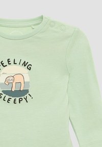 Lichtgroen langslavende baby shirt met twee schouderknopen, voorzien van een illustratie van een slaperige luiaard en de tekst "Ik voel me slaperig!"