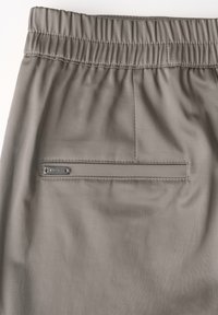 Grå shorts med elastisk midja och en slät textur, med en bakficka och en liten märkeslapp nära sömmen.