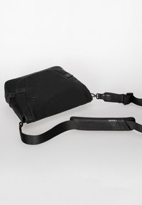 Black messenger bag with a sleek design, made of durable material. Features a detachable strap, textured accents, and subtle branding.