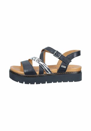 Black platform sandal with tan footbed, two solid black straps, one zebra-striped strap, and an adjustable buckle closure.