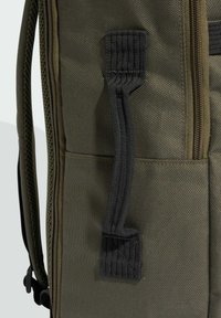 Olijfgroene rugzak met een gestructureerde stof, versterkte ritsen en een zwart gespen handvat aan de zijkant voor gemakkelijk dragen.