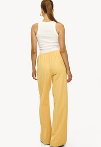 Geel gestreepte wijde broek met een elastische tailleband, voorzien van verticale strepen in het roze. Gemaakt van een gladde, lichte stof.