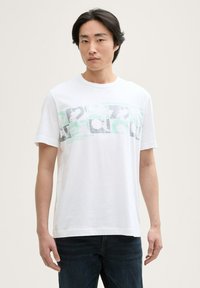 Hvid bomulds T-shirt med et grafisk design i grå og mintgrøn. Rund hals og korte ærmer, med en afslappet pasform.