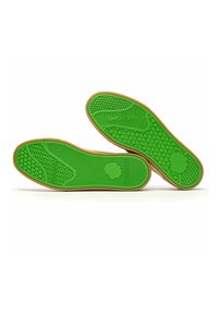 Suelas de zapatos de goma verdes con patrones texturizados, que presentan diseños hexagonales y lineales, y un borde marrón que resalta la forma.