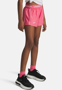 Pink athletic shorts with a wide, elastic waistband and reflective side stripes. Worn with black sneakers and pink ankle socks.