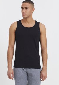 Zwarte katoenen tanktop met een ronde hals, met een slim fit ontwerp. Draagt met grijs gemêleerde joggingsbroek. Glad textuur.