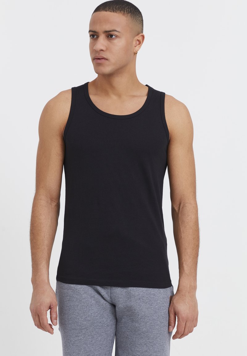 Must mustriba musta tank top ümmarguse krae ning slim fit disainiga. Kanna hallide heledate dressipükstega. Sile tekstuur.