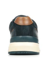 Zapatillas para hombre con parte superior de ante azul marino, acento de cuero marrón en el talón y suela de goma crema. Presenta costuras en contraste.