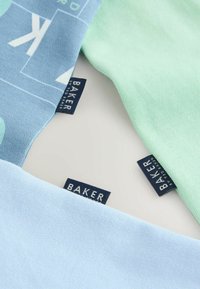 Trīs tekstila gabali zilā un piparmētru krāsā, demonstrējot mīkstu kokvilnas audumu ar redzamām zīmola etiķetēm tumši zilā krāsā. Katram gabalam ir gluda tekstūra.