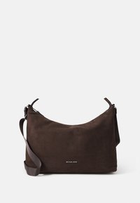 Hnědá semišová kabelka přes rameno zaobleného tvaru, s nastavitelným popruhem a stříbrným logem v přední části. Hladká textura a minimalistic design.