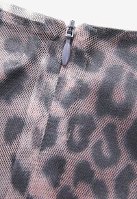Černá síťovina s leopardím potiskem a viditelným zipovým uzávěrem. Textura je průhledná, zvýrazňující zvířecí vzor v tmavých a jemně růžových tónech.