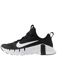 Sort og hvid Nike træningssko med åndbart mesh-øvre, hvid sål med dybe riller og stort hvidt Nike swoosh på siden.
