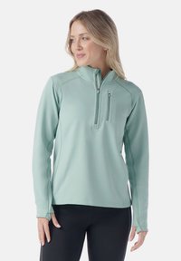 Licht teal lange mouw pullover met een neklijn en een halve ritssluiting aan de voorkant. Heeft een ritszak op de borst en aansluitende manchetten. Gladde textuur.