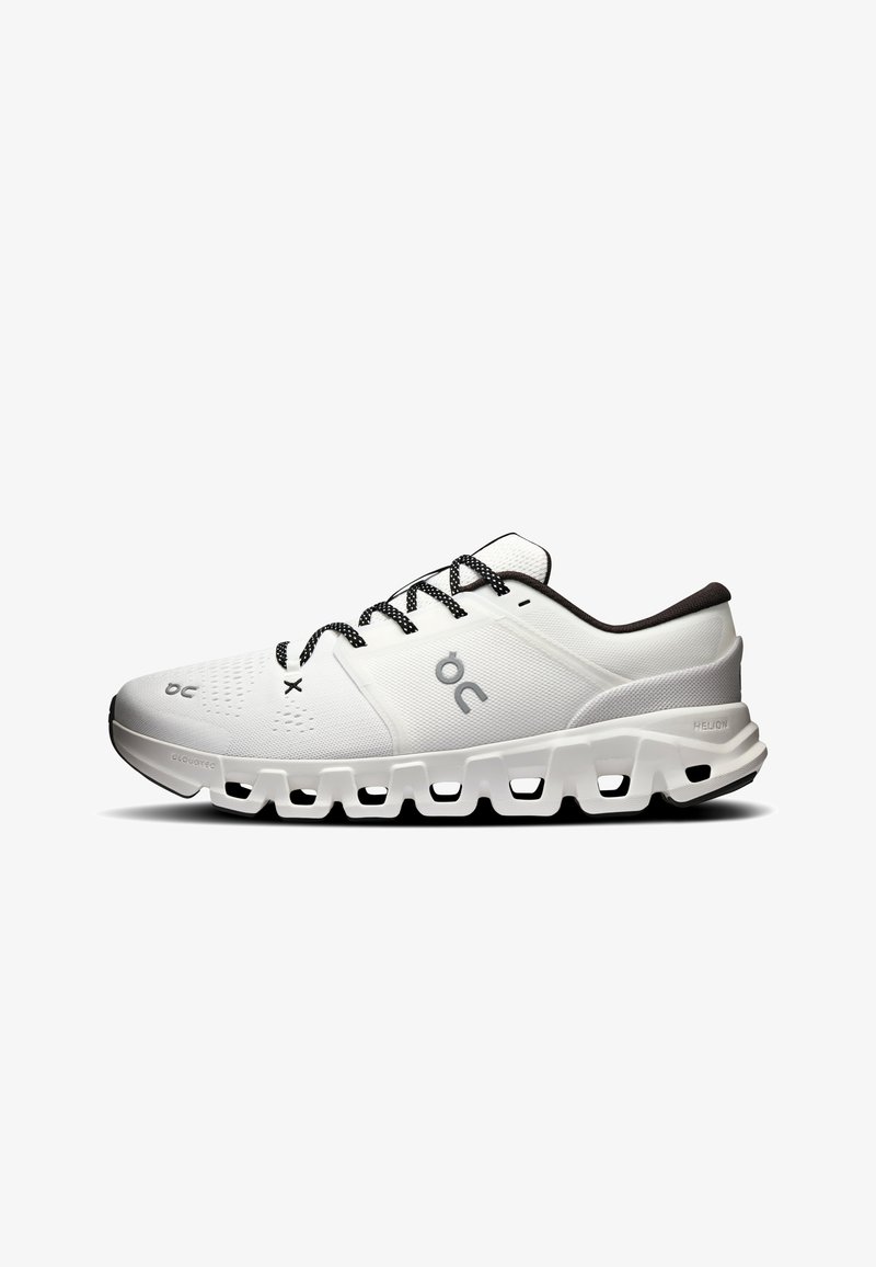 Chaussure de sport blanche avec lacets noirs et blancs, tige en mesh respirant et semelle épaisse segmentée conçue pour l'amorti et le maintien.