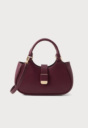 Petit sac à main en cuir bordeaux de forme arrondie, avec des poignées courtes et courbées, une bandoulière amovible et une fermeture dorée sur le rabat avant.
