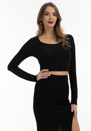 Top scurt negru, cu maneci lungi, cu decolteu rotund, realizat dintr-un material elastic, asortat cu o fustă înaltă, care are o deschidere.