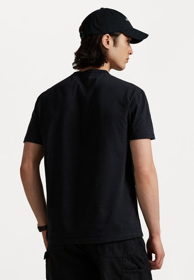 Svart bomull T-skjorte med korte ermer, rund hals, avslappet passform, brukt med svarte cargo-bukser, minimalistisk design, ingen synlige logoer eller mønstre.