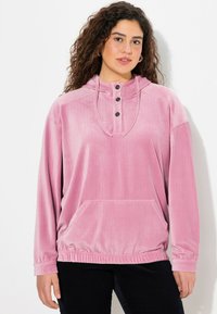 Rosa Cordpullover mit hohem Kragen, Knopfleiste mit drei Knöpfen und Fronttasche. Mit elastischen Bündchen und Saum für eine entspannte Passform.