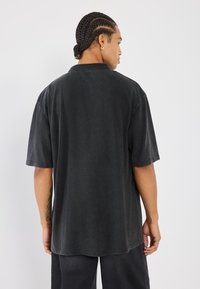 Svart oversized t-skjorte laget av myk stoff, med en avslappet passform, korte ermer og en enkel halslinning.