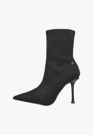 Botín negro de tobillo hecho de tela suave, con punta afilada, tacón de aguja alto y parte superior elástica con costuras decorativas.