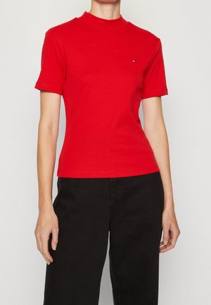 Czerwona koszulka z krótkim rękawem i wysokim kołnierzem. Wykonana z bawełny, z małym logo na piersi i dopasowanym krojem.